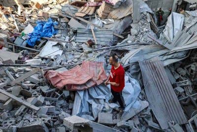 Seorang lelaki berdiri di atas runtuhan sebuah bangunan yang terkena serangan Israel di kem Bureij untuk pelarian Palestin di tengah Semenanjung Gaza. Foto AFP