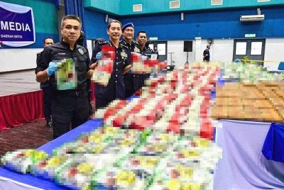 Mat Zani (kiri) bersama Mohd Khairi (dua dari kiri) menunjukkan antara dadah yang dirampas dalam dua serbuan berasingan di Sungai Setiu pada 23 April lalu.