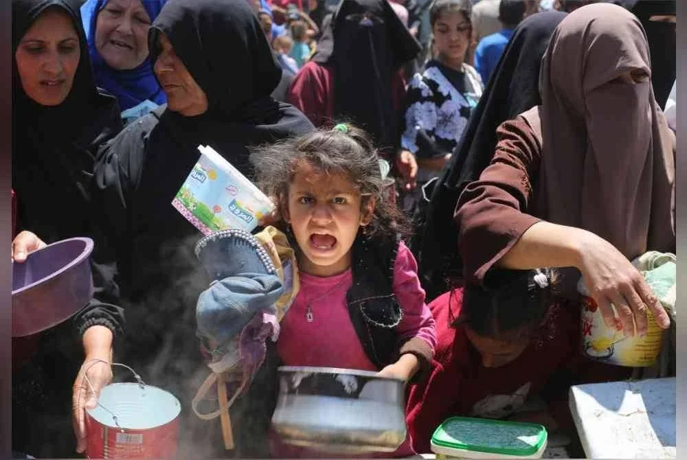 Penduduk Palestin beratur untuk makanan panas di dapur amal di kem pelarian Nuseirat, Gaza tengah. - AFP