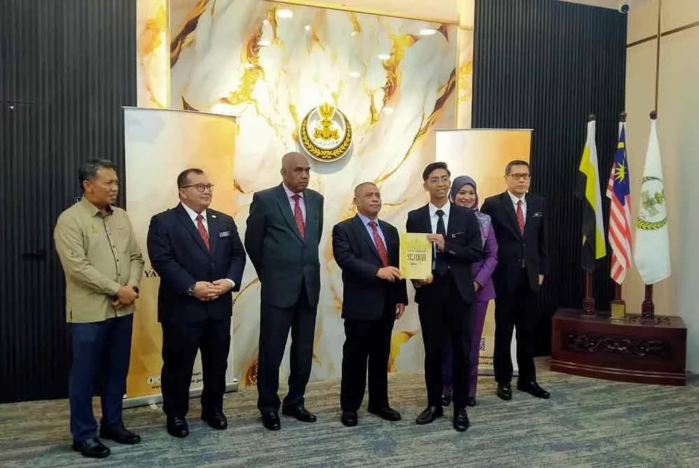 Saarani (tengah) menyampaikan buku rujukan tambahan kepada wakil pelajar sebagai gimik Majlis Pelancaran Inisiatif Buku Rujukan Tambahan SPM 2025 di Foyer Pejabat Menteri Besar Perak pada Rabu.