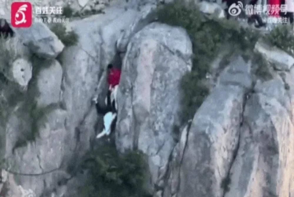 Situasi getir mengerikan yang dilalui oleh pasangan tersebut selepas terjatuh ketika cuba memanjat penghadang keselamatan di kawasan Gunung Tai. Sumber foto Weibo