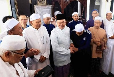 Anwar (depan, empat dari kiri) beramah mesra bersama ahli kariah ketika hadir bagi menunaikan solat Jumaat di Surau Al-Iman, Presint 9, Putrajaya pada Jumaat. FOTO: Bernama 