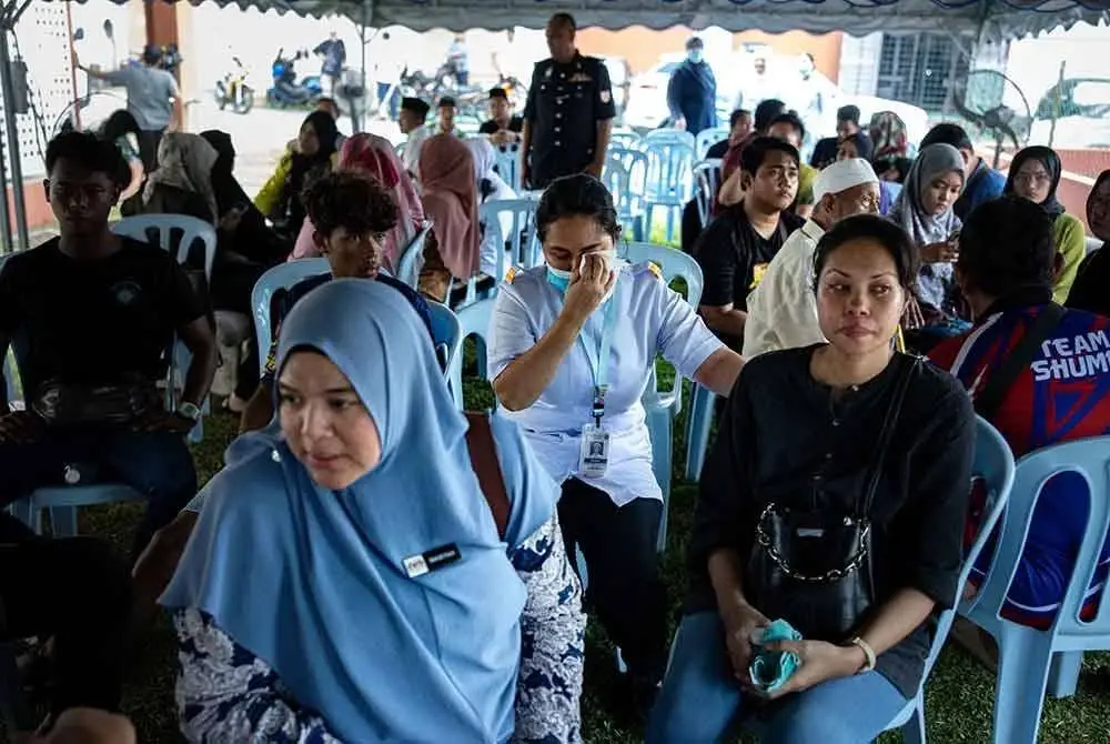 Waris dan kenalan mangsa mula berkumpul di pekarangan Unit Forensik Hospital Teluk Intan ekoran kejadian kemalangan yang membabitkan lori pasukan Unit Simpanan Persekutuan (FRU) dengan lori muatan batu di Jalan Chikus-Sungai Lampam hari ini. Foto Bernama