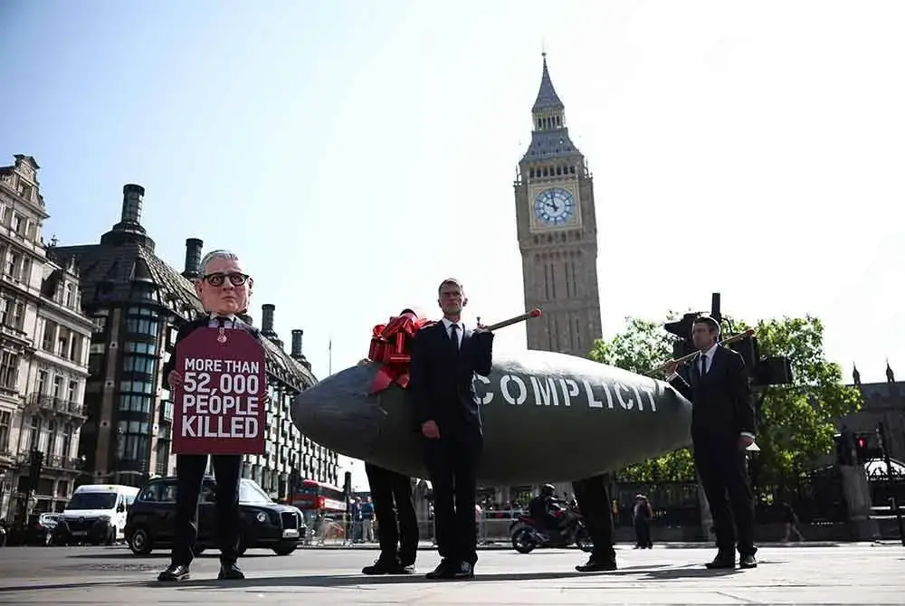 Seorang penunjuk perasaan yang berpakaian seperti Perdana Menteri Britain, Keir Starmer, bergambar di hadapan replika bom MK-84 yang dilabelkan dengan perkataan 'Complicity' (bersubahat) dan tag yang tertulis 'Lebih 52,000 orang terbunuh', merujuk kepada angka korban di Gaza sejak serangan Israel bermula. Foto AFP