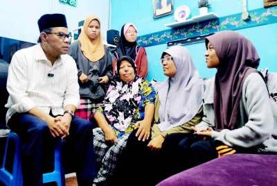 Haswati (duduk, tengah) berkata sesuatu kepada Menteri Dalam Negeri, Datuk Seri Saifuddin Nasution yang menziarahi mereka sekeluarga di kediaman kuarters FRU di Sungai Senam pada Rabu.