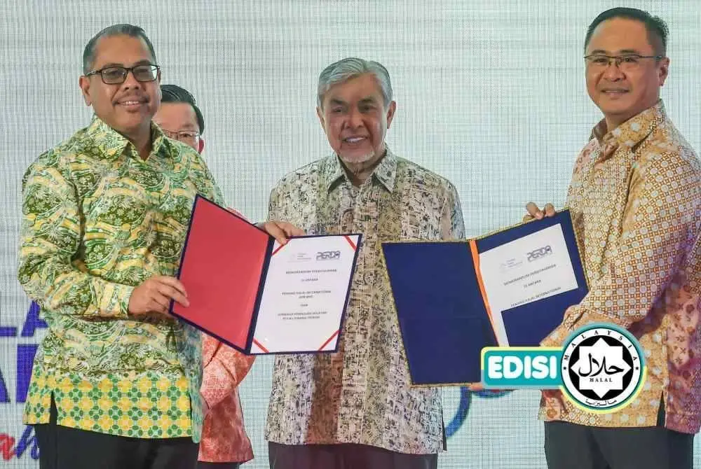 AHMAD ZAHID (tengah) menyaksikan Pengurus Besar Lembaga Kemajuan Wilayah Pulau Pinang (PERDA) Mohd Asri Baharum (kiri) bertukar Memorandum Persefahaman dengan Ketua Pegawai Eksekutif Penang Halal International (PHI) Mohd Azraie Ramli (kanan) pada Pelancaran Majlis Pembangunan Industri Halal Pulau Pinang. Foto Bernama