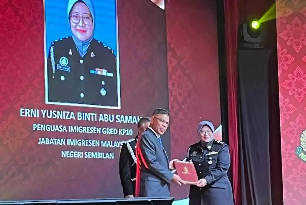 Saifuddin Nasution menyampaikan anugerah kepada salah seorang penerima pada Majlis Anugerah Perkhidmatan Cemerlang 2024 Jabatan Imigresen di Putrajaya pada Jumaat.