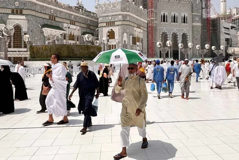Seorang bakal jemaah haji menggunakan payung untuk berlindung dari panas matahari berhampiran Masjidil Haram, Makkah.
