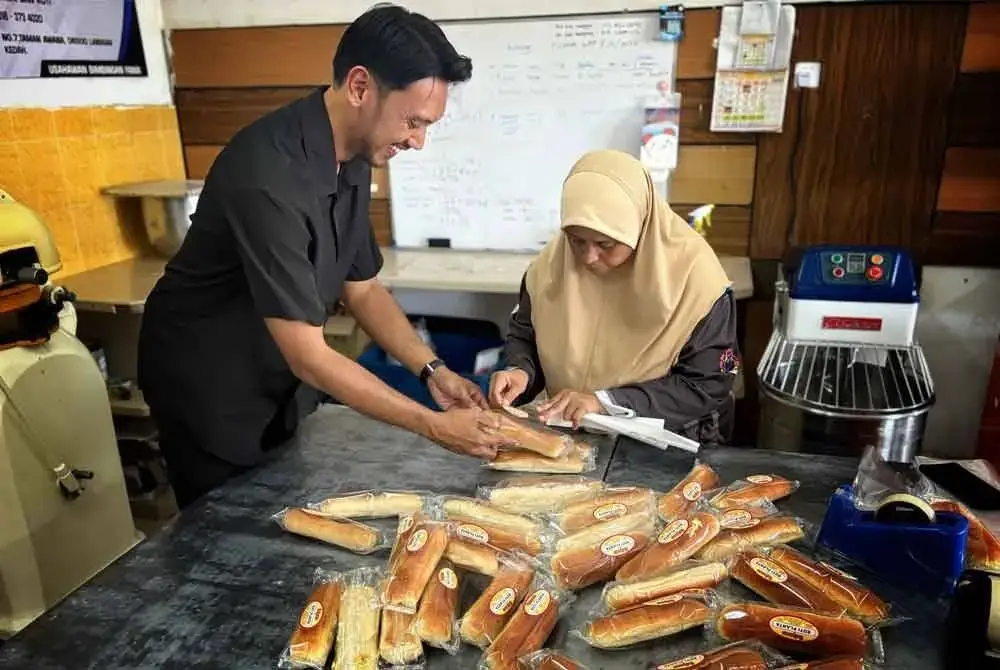 Shahmiakmal membantu pekerjanya melekatkan label pada roti.