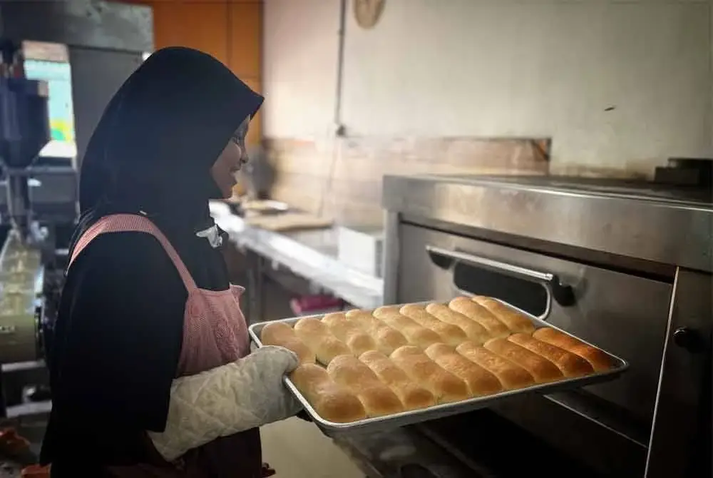 Seorang pekerja mengeluarkan roti yang siap dibakar.