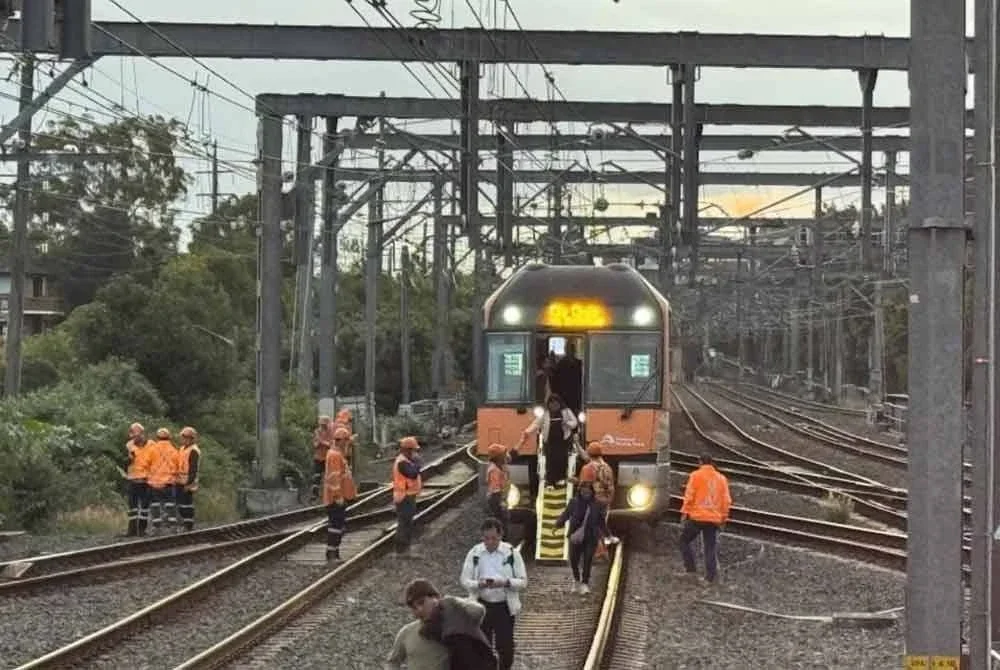 Pasukan teknikal memindahkan penumpang dari tren ke stesen terdekat.
