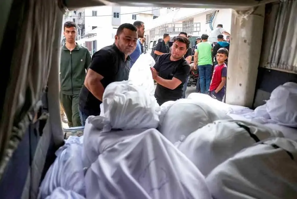 Penduduk Palestin menyusun jenazah mangsa yang terbunuh dalam serangan udara Israel, ke dalam sebuah kenderaan di Hospital Al-Shifa, Bandar Gaza sebelum dikebumikan.