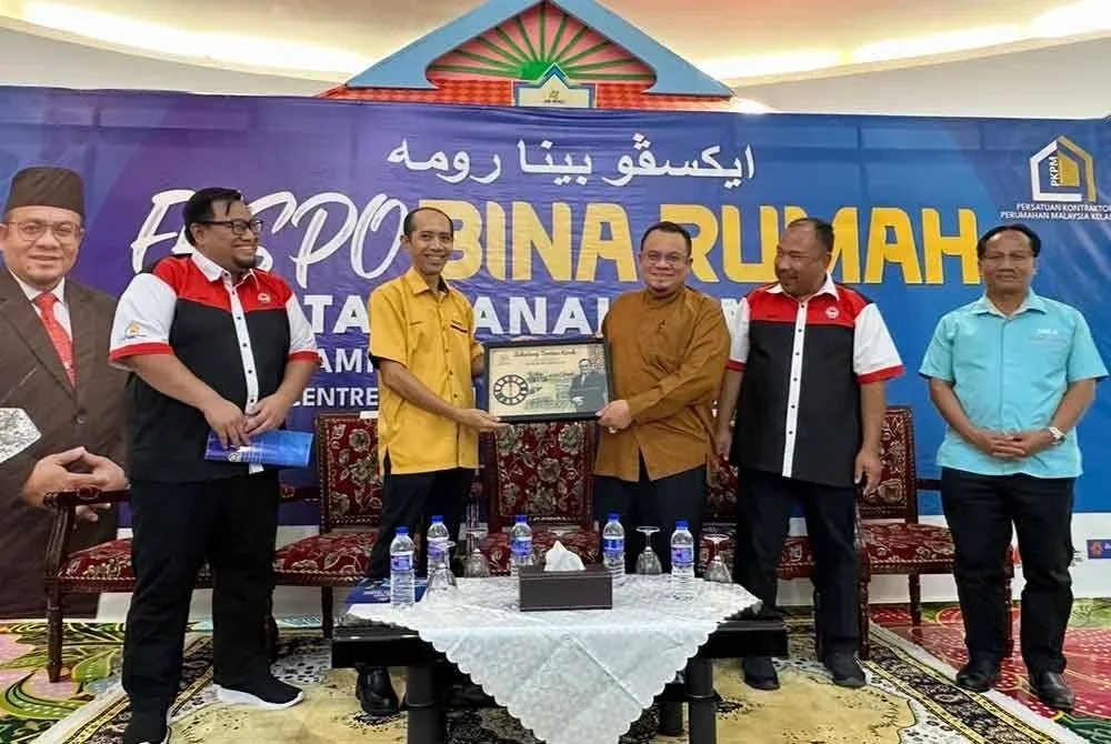 Hasniro (dua dari kiri) menyampaikan cenderamata kepada Hilmi ketika Majlis Perasmian Ekspo Bina Rumah Atas Tanah Sendiri di Kota Bharu pada Jumaat.