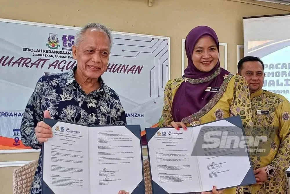 Muhammad Nasir dan Izzan Haslinda menunjukkan MoU antara Karangkraf dengan SK Tanah Puteh selepas majlis perasmian Mesyuarat PIBG SK Tanah Puteh kali ke-44 di Dewan Gemilang, Pekan pada Sabtu. Foto Sinar Harian.