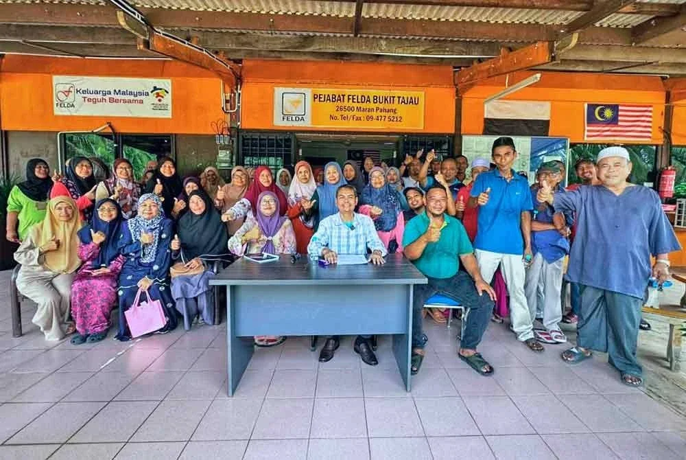 Wan Azeman (tengah, duduk) bersama sebahagian penduduk dan peserta skim terbabit yang hadir dalam sidang akhbar tersebut.