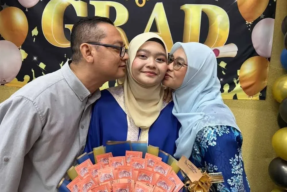 Tuan Nur Hannah (tengah) menerima ciuman daripada ibu bapanya.