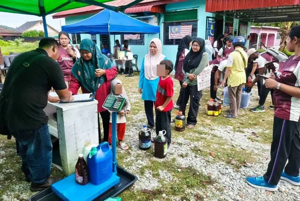 Orang ramai beratur menunggu giliran menyerahkan minyak masak terpakai untuk dikitar semula.