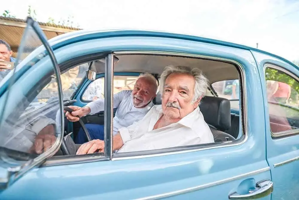 Jose Mujica (kanan) menaiki kereta Volkswagen Beetle berwarna biru langit bersama Presiden Brazil, Luiz Inacio Lula da Silva. Foto AFP