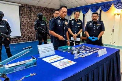 Dzulkhairi (kiri) menunjukkan pelbagai jenis dadah yang berjaya dirampas dalam serbuan di Jasih Bestari ketika sidang akhbar di IPK Melaka, di Bukit Beruang, di sini, pada Selasa.