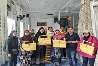 Jurina (empat dari kiri) menyerahkan rehal kepada Jamil (dua dari kanan) bagi melengkapkan kemudahan Rumah Mengaji Mamie di Kampung Tengah.