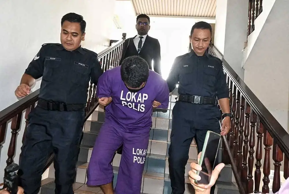 Tertuduh (tengah) didakwa di Mahkamah Sesyen Melaka pada Jumaat.