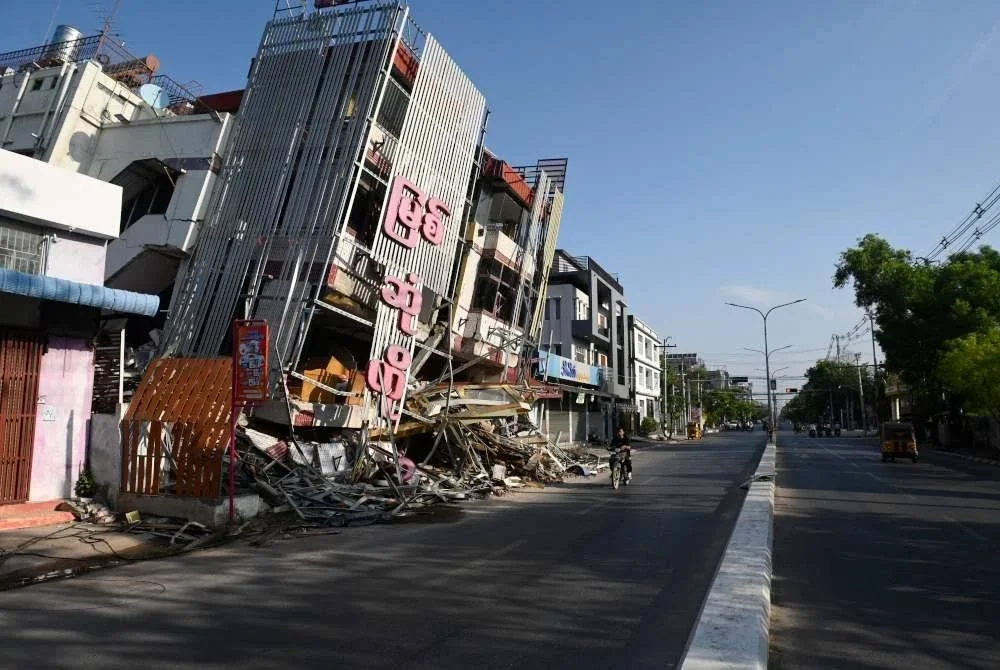 Seorang lelaki menunggang motosikal melepasi bangunan yang rosak di Mandalay berikutan gempa bumi yang dahsyat pada 28 Mac. Foto AFP