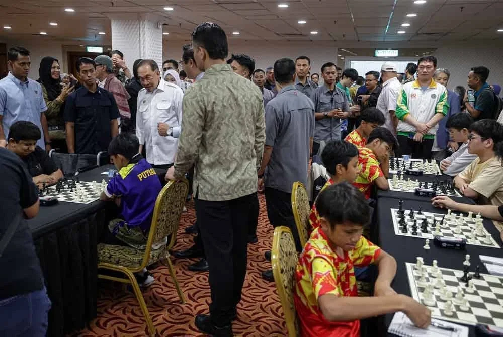 Anwar meluangkan masa melawat cucunya Sulaimaan (kanan) yang beraksi pada MCF-NSTP dalam kategori Open Rapid Team sempena PBAKL 2025 di WTCKL hari ini. - Foto: Bernama