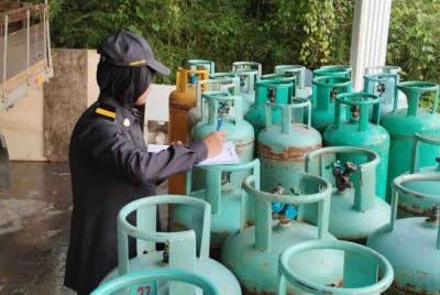 Penguat kuasa KPDN memeriksa LPG yan disita di sebuah stor haram di Mantin.