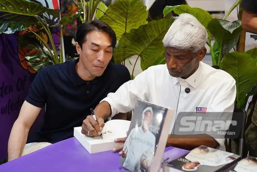 Rajagobal (kanan) menandatangani buku autobiografinya 'Inilah Saya - K Rajagobal' sambil ditemani Khairul Fahmi di reruai Karangkraf sempena PBAKL 2025 pada Sabtu. Foto Sinar Harian - ROSLI TALIB