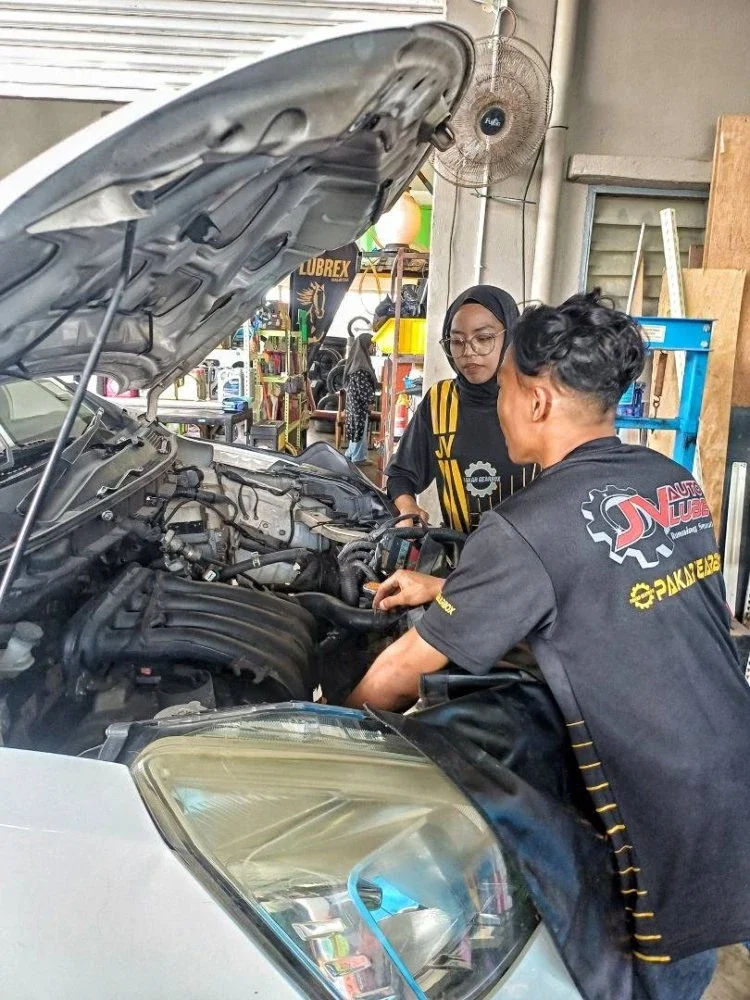 Sofea Nabila sedang memeriksa enjin kenderaan bersama pekerjanya.