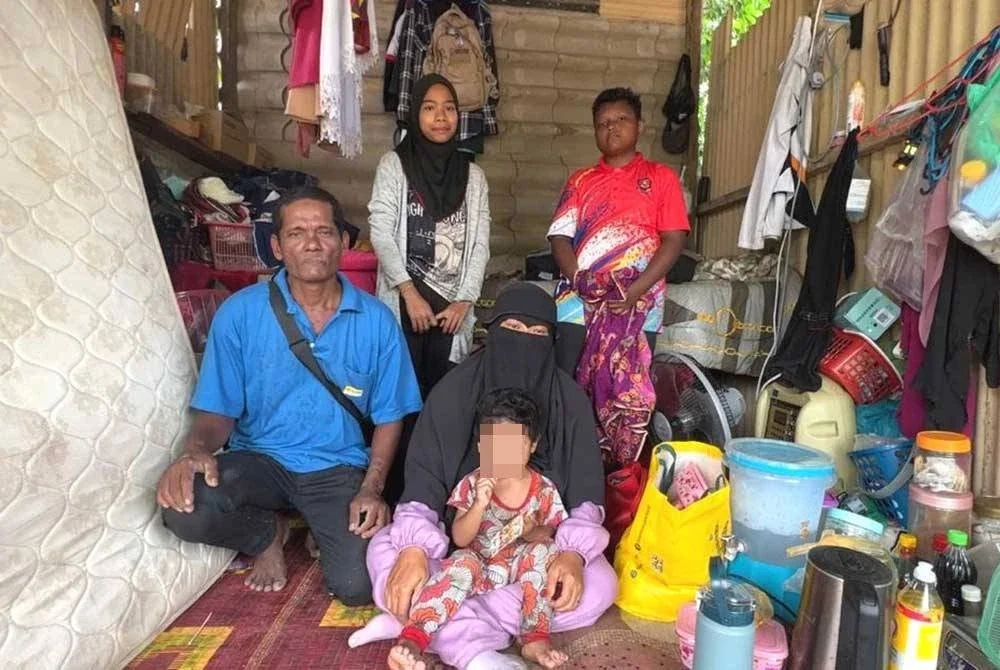 Mazilah (tengah) bersama suami, Mat Nasir (kiri) berada di sebuah pondok yang menjadi tempat tinggal mereka sekeluarga sejak awal tahun ini.