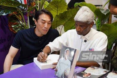 Rajagobal (kanan) menandatangani buku autobiografinya 'Inilah Saya - K Rajagobal' sambil ditemani Khairul Fahmi di reruai Karangkraf sempena PBAKL 2025 pada Sabtu. Foto Sinar Harian - ROSLI TALIB