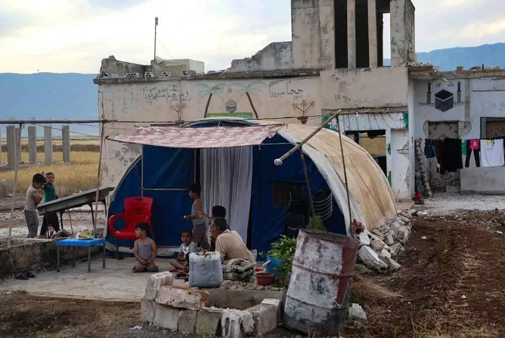 Penduduk, Aref Shamtan (kanan) duduk di luar sebuah khemah di kampung al-Hawash di wilayah Hama, tengah barat Syria. Foto AFP