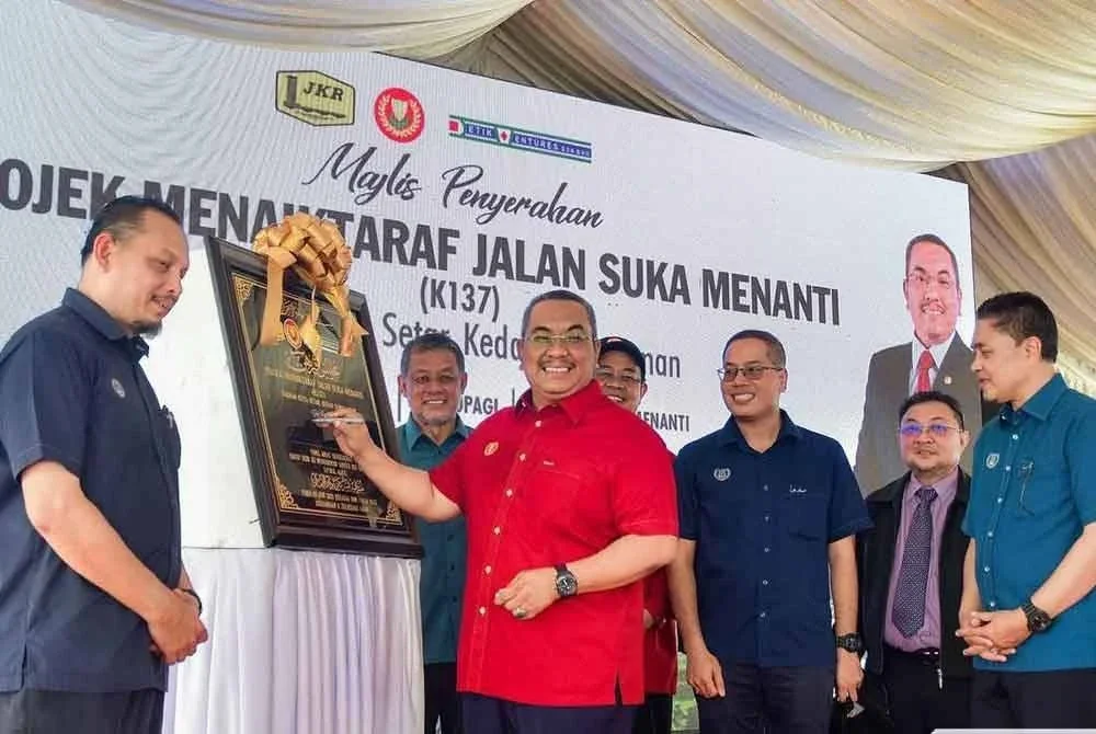 Muhammad Sanusi menandatangani plak sempena penyerahan projek siap menaik taraf Jalan Suka Menanti (K137) di Suka Menanti pada Selasa.