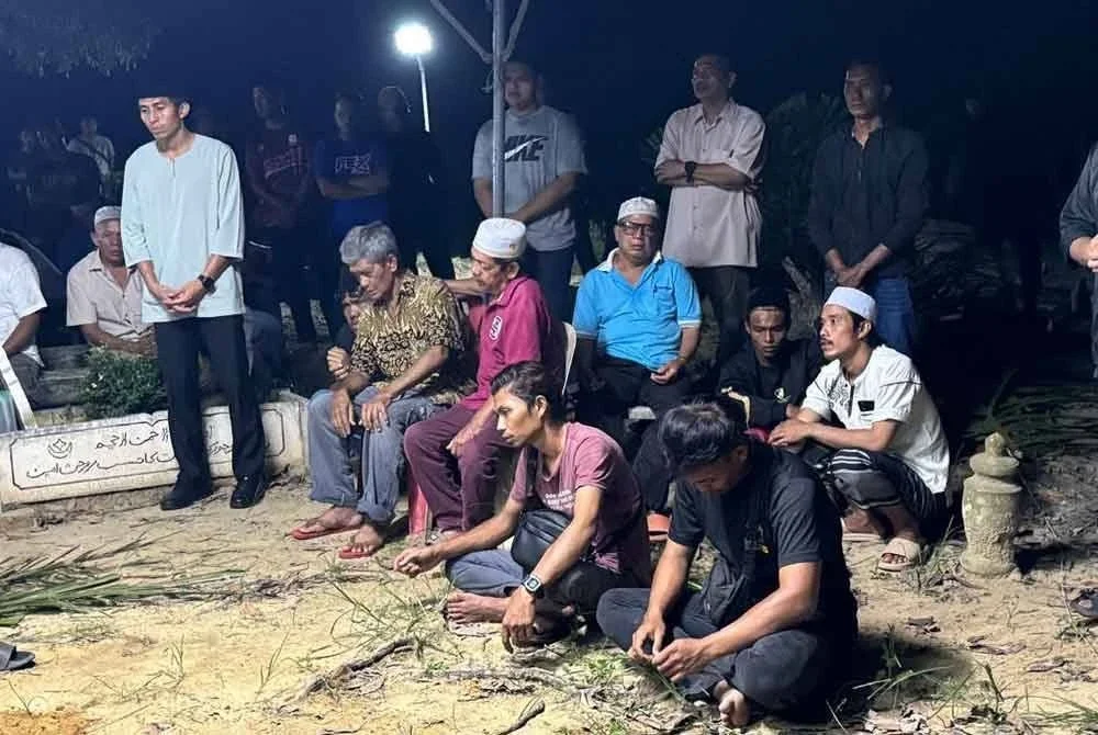 Bapa Iecah (duduk, kiri) kelihatan sebak semasa pengebumian anaknya di Tanah Perkuburan Islam Kampung Pengkalan Kota, Durian Chondong, Tangkak pada Rabu.