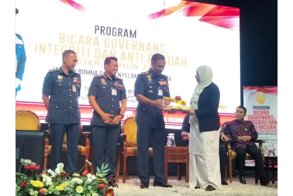 Nor Hisham (dua, kiri) menyampaikan cenderamata kepada Nurhayati.