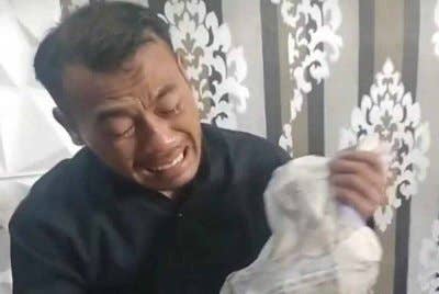 Wadison menangis seperti histeria sambil memegang baju isterinya. Foto Agensi