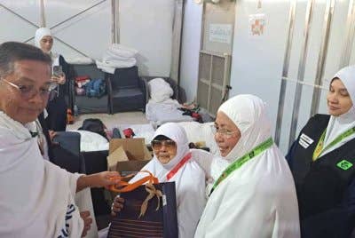 Mohd Na'im (kiri) menyantuni seorang jemaah haji yang menyertai Program Peneman.