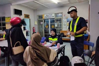 Dua beradik yang disaman mendengar penerangan pegawai JPJ selepas motosikal mereka disita.