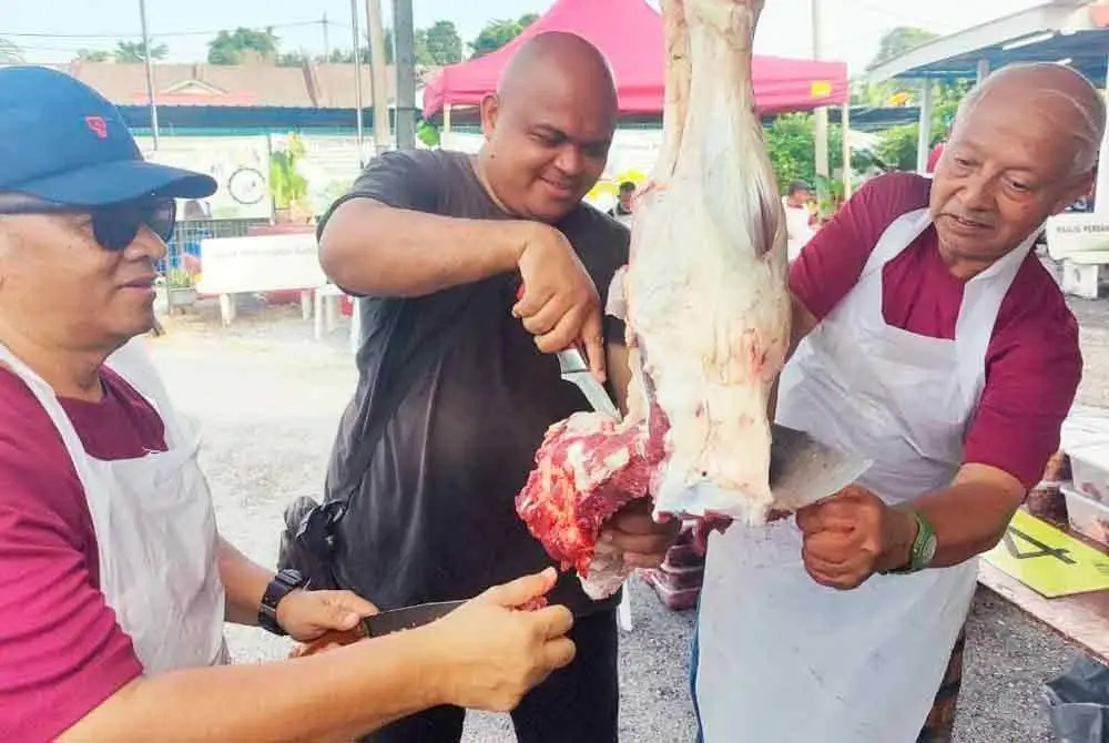 Roslan (kanan) melapah daging pada Program Ibadah Korban di Taman Bukit Jati, Klang pada Ahad.