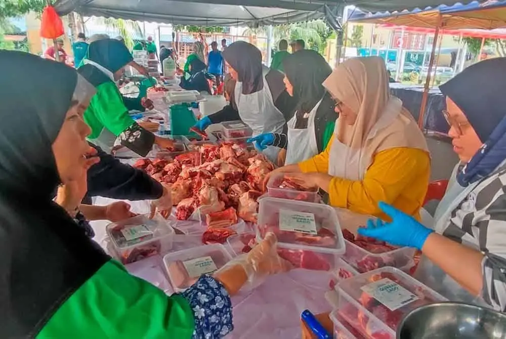 Sukarelawan sedang memasukkan daging korban dalam bekas untuk diagihkan kepada penerima.