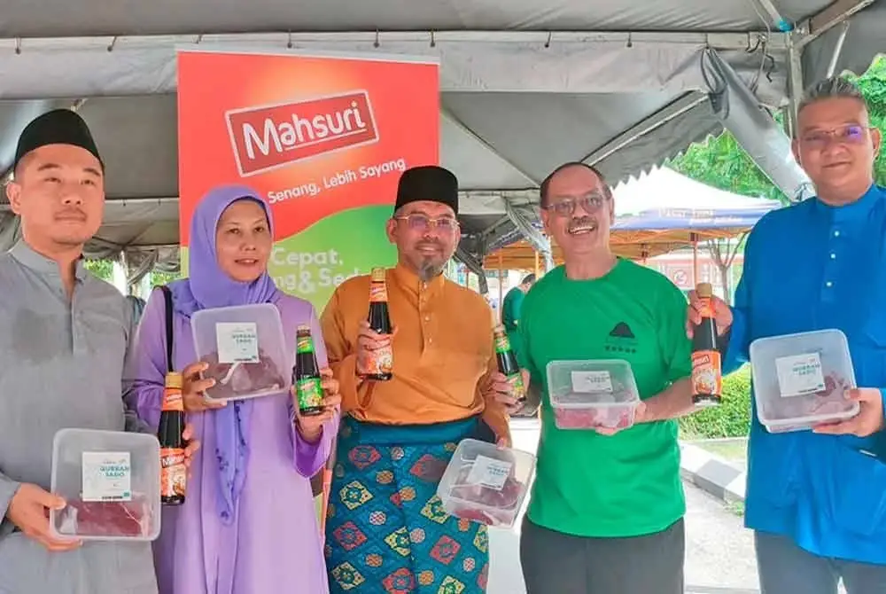 Mohd Jazri (kanan) menunjukkan daging korban yang diagihkan kepada penerima pada Majlis Korban Asnaf Mahsuri di Masjid Ar-Rahimah, Kampung Pandan.