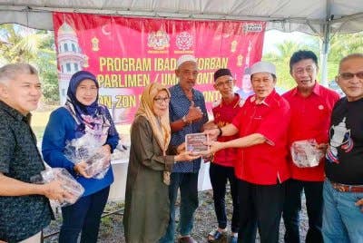 Ahmad (dua, kanan) menyerahkan agihan daging korban di Kampung Parit Stan, Benut pada Ahad.