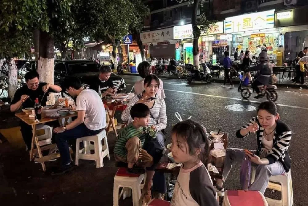 Orang ramai makan berhampiran restoran di tepi jalan di Chengdu, wilayah Sichuan, China. Foto Reuters