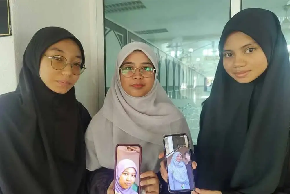 Nurul Izzati (tengah) bersama rakannya, Nur Syakirah (kanan) dan Nur Hasya (kiri) menunjukkan gambar Sufea (kiri) dan Amni (kanan) yang terkorban dalam nahas bas di Jalan Raya Timur–Barat, Banun, Gerik awal pagi Isnin.