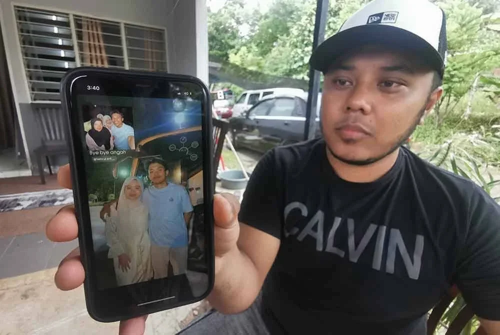 Izwan Iskandar menunjukkan gambar arwah sepupunya besama ahli keluarga yang dirakam sebelum bertolak menaiki bas.