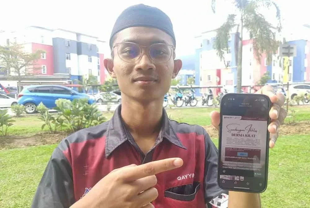 Muhammad Qayyim menunjukkan poster mengenai kutipan derma kilat yang dilancarkan berikutan kejadian nahas bas membabitkan penuntut UPSI di Jalan Raya Timur–Barat, Banun, Gerik awal pagi Isnin.