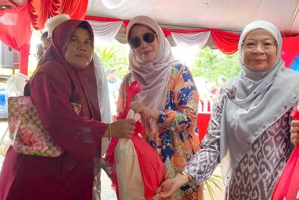 Tunku Noor Hayati (tengah) menyampaikan bakul makanan kepada masyarakat Orang Asli tanpa mengira agama.