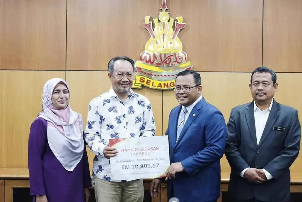 Amirudin (kanan) menyampaikan pampasan kepada waris Ku Adib Aizad.