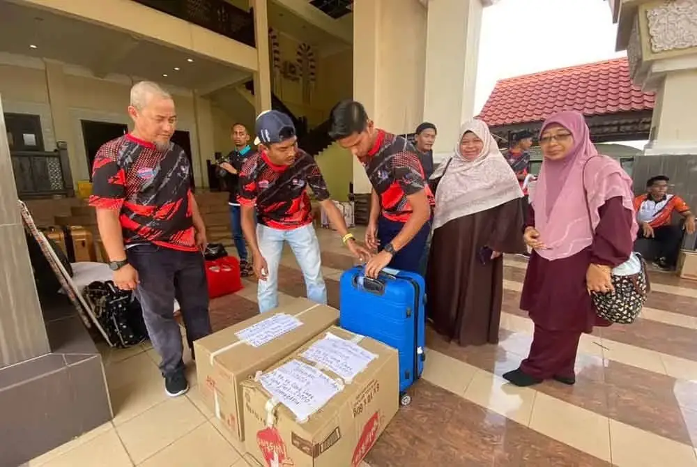 Mohd Azlan (kiri) bersama petugas yang menguruskan barangan milik kesemua 15 pelajar UPSI yang menjadi mangsa nahas kemalangan bas di Gerik, Perak.